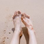 砂浜の上に投げ出された素足の画像