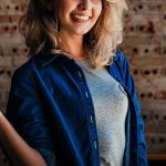 右手をぐっと握りしめ、笑顔でやる気を見せる女性