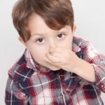 花をつまんでこちらを見るチェック柄のシャツを着た男の子の画像1