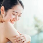すべすべになった二の腕を触りながら微笑む女性の画像