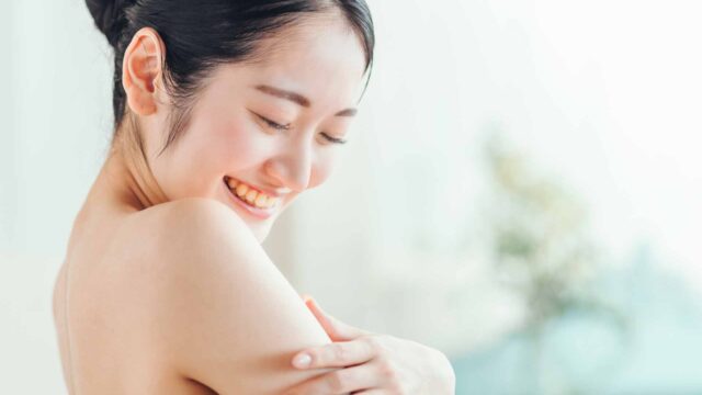 すべすべになった二の腕を触りながら微笑む女性の画像