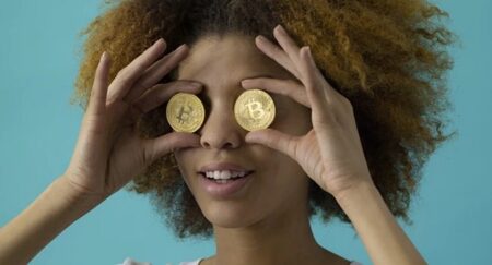 人_両目にビットコインを当てて遠くを見る表情の女性