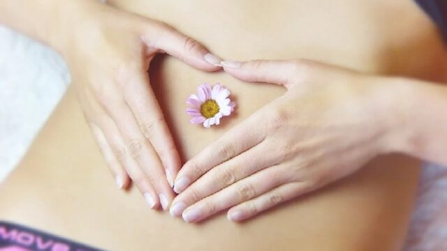 お腹に花を置いた女性の腹部の画像