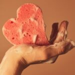 人_泡に覆われたスポンジと手の画像