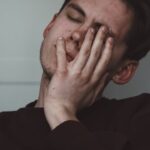 人_痛みで顔をしかめる男性