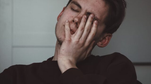人_痛みで顔をしかめる男性
