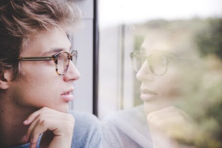 人_窓から外を眺める男性の横顔