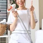 サロン_脱毛器をもって人差し指を立てて笑顔を向ける脱毛サロンのスタッフ