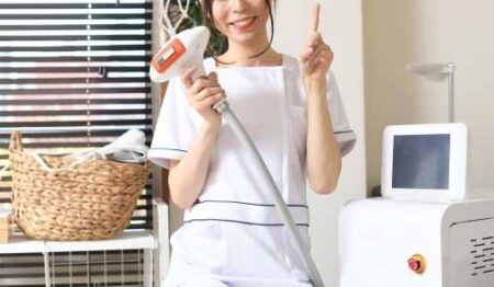 サロン_脱毛器をもって人差し指を立てて笑顔を向ける脱毛サロンのスタッフ