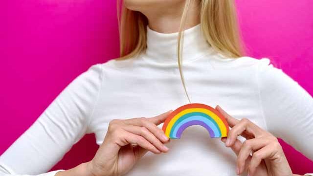 人_胸の前で虹を持つ女性の画像