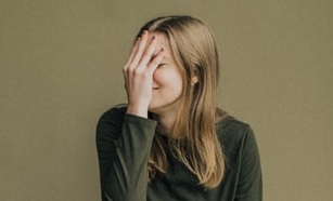 人＿恥ずかしそうに手で顔を覆う女性の画像